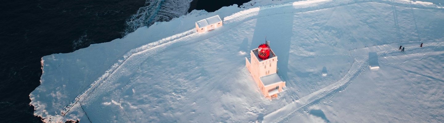 A red boat rests on a large iceberg, contrasting against the icy blue surroundings.